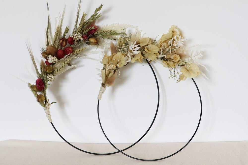 Zwei runde Metallringe mit getrockneten Blumen und Gräsern an der oberen Hälfte