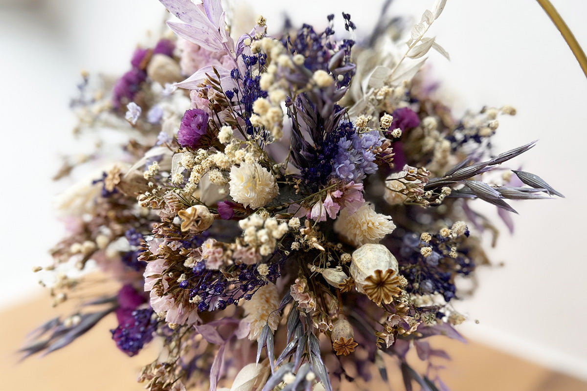 Nahaufnahme eines Trockenblumenballs in lila Pastellfarben in einem goldfarbenen runden Metallring